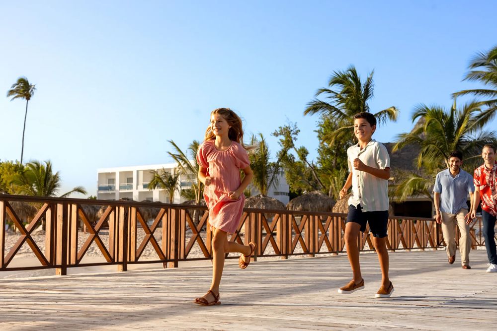 Pareja paseando por la pasarela de madera del Sunscape Dominicus junto a la playa