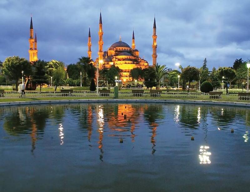 La Mezquita Azul iluminada al anochecer, reflejada en la fuente de Sultanahmet