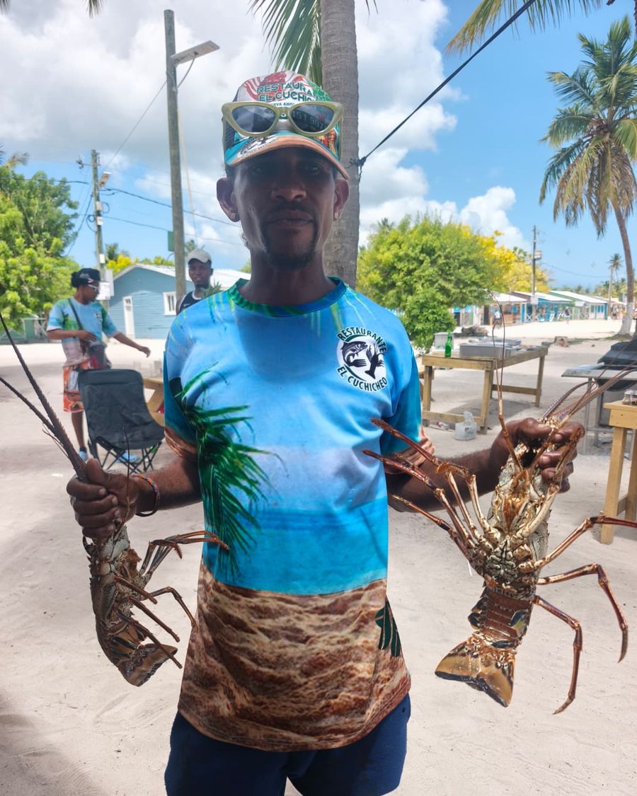 Pescador mostrando langostas frescas en Mano Juan, Isla Saona